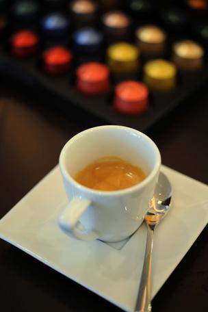 A cup of Nestle Nespresso coffee is seen in front of coffee capsules in one of