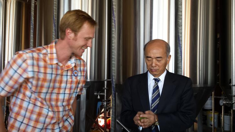 Charlie Berger, co-owner of Denver Beer Co., demonstrates how to crush and smell hop flowers at his brewery to Kenichiro Sasae, Japanese ambassador to the United States.