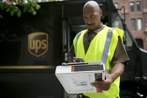 A United Parcel Service Inc. (UPS) employee scans a package while making a delivery.