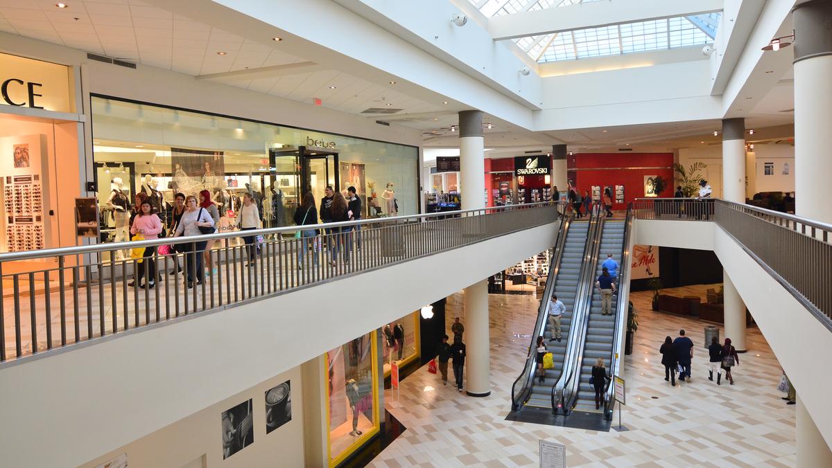 Group of people shoppers on busy indoor down escalator Westfield