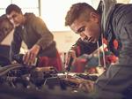 Auto mechanic working on a car engine in repair shop.