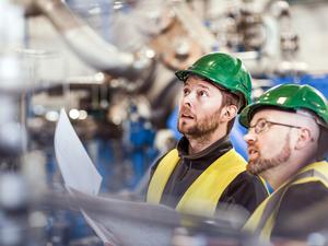 Male colleagues analysing machine in industry