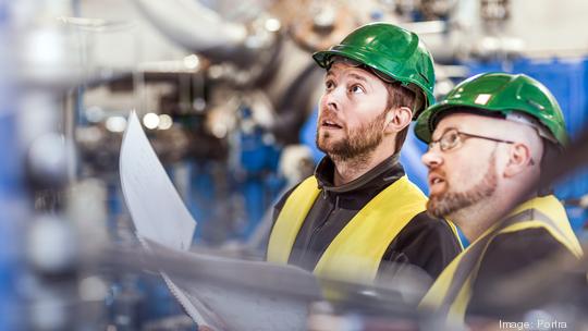 Male colleagues analysing machine in industry