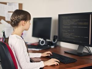 Little girl learning to code on desktop computer at home