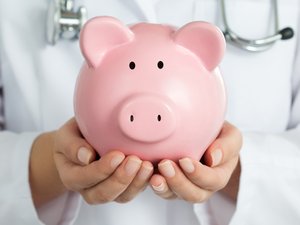 Female Doctor Holding Piggy Bank