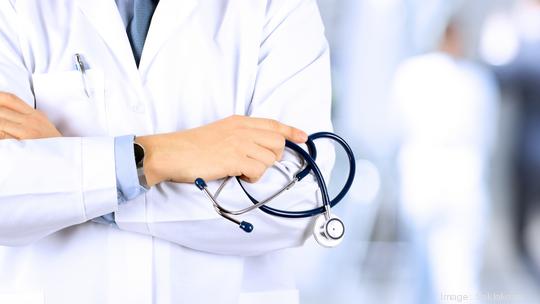 Portrait an unknown male doctor holding a stethoscope behind