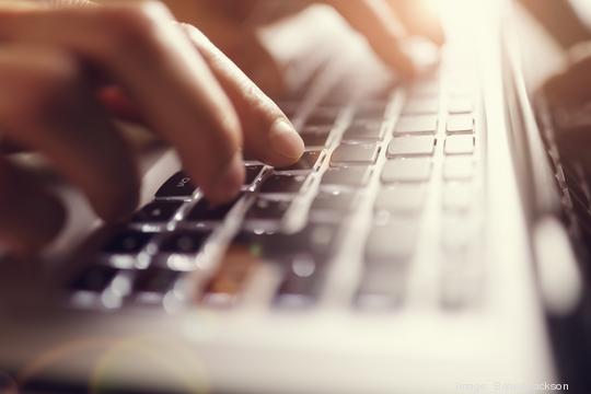 Hands typing on laptop computer