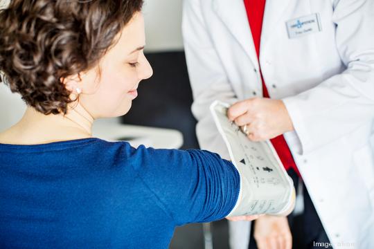 Nurse checking blood pressure of young woman