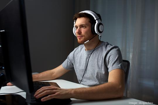 man in headset playing computer video game at home