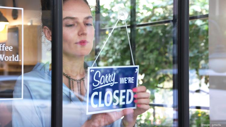 A woman hangs a closed sign on a door.