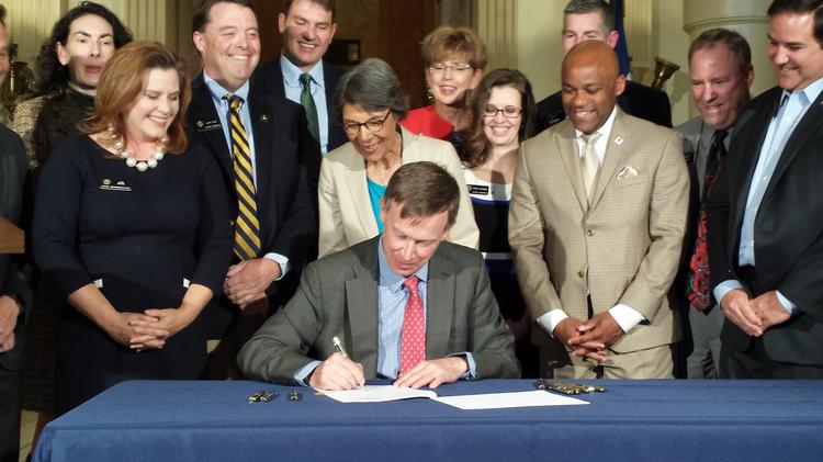 Colorado Gov. John Hickenlooper signs a construction-defects reform bill Tuesday while surrounded by legislative sponsors and supporters of the effort.