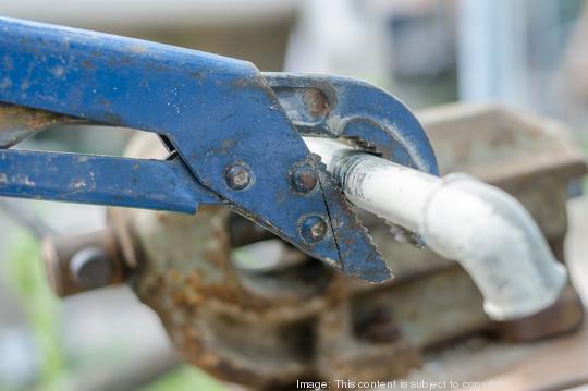 Old blue wrench unwind elbow from pipe, close up