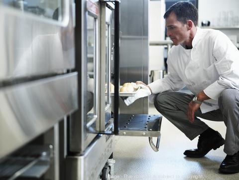 Chef taking food from oven in restaurant kitchen