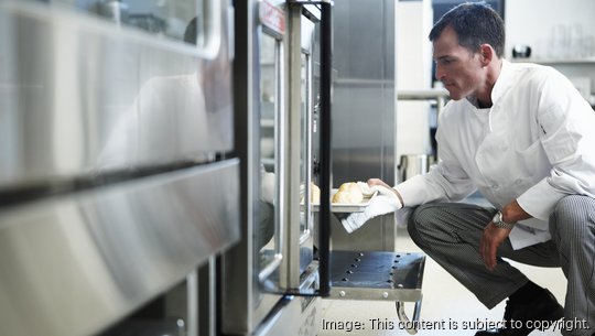 Chef taking food from oven in restaurant kitchen