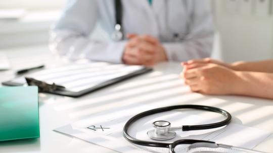 Stethoscope next to hand of doctor  reassuring her female patient. Medical ethics and trust concept