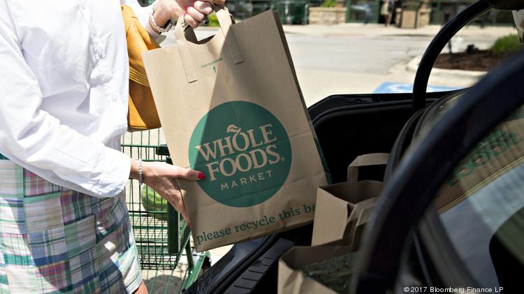 A customer loads shopping bags into a vehicle outside a Whole Foods Market Inc. location in Naperville, Illinois, U.S., on Friday, June 16, 2017. Amazon.com Inc. will acquire Whole Foods Market Inc. for $13.7 billion, a bombshell of a deal that catapults the e-commerce giant into hundreds of physical stores and fulfills a long-held goal of selling more groceries.