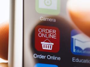 Hand touching online ordering app on phone screen