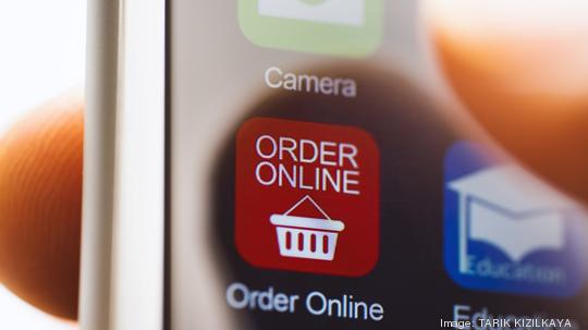 Hand touching online ordering app on phone screen