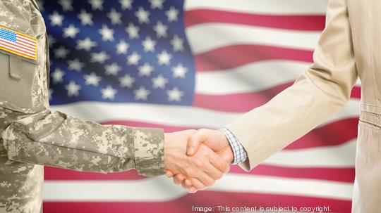 USA military man in uniform and civil man in suit shaking hands with national flag on background - United States