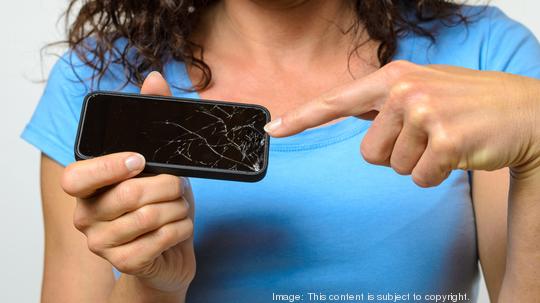 Midsection Of Woman Pointing At Broken Mobile Phone Display