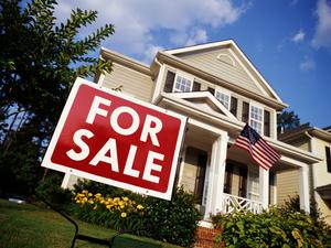 House with American flag and 'for sale' sign, low angle view