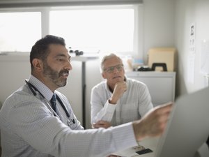 Male doctor showing computer to senior patient in doctor