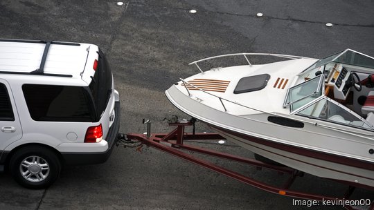 White SUV pulling white speed boat on trailer from above