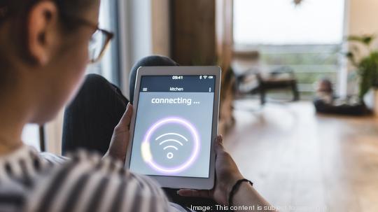 Woman using tablet with wifi symbol at home Internet of Things