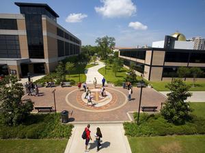 Students walking past campus seal at University of St. Thomas.