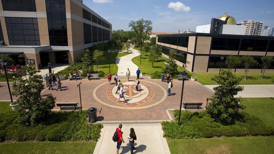 Students walking past campus seal at University of St. Thomas.