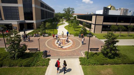 Students walking past campus seal at University of St. Thomas.