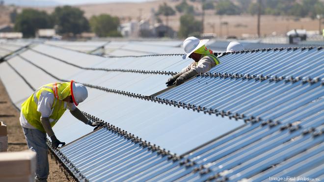 Workers actively engaging in solar panel maintenance and installation at a large-scale solar farm.