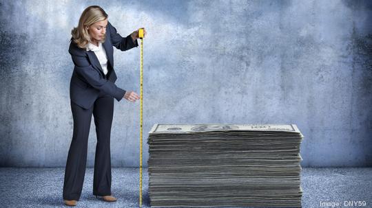 Businesswoman Measuring A Stack Of Money With Tape Measure