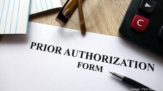 Prior authorization form with pen, calculator and glasses