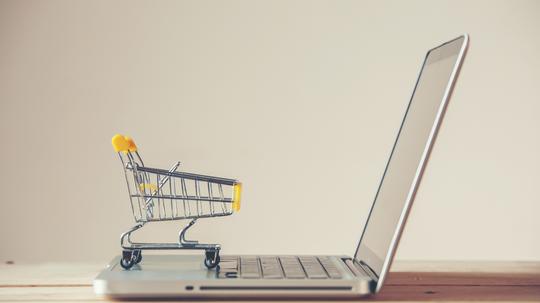 Small Shopping Cart On Laptop With Copyspace : Online Shopping Concept. E-commerce.