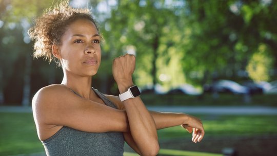 Woman wearing smart watch stretching at park