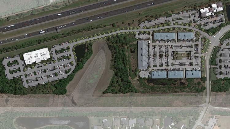 In the site plan, the grey roofs toward the righthand side belong to the complex where the company is currently located (in five separate office spaces). The larger building on the left with the white roof indicates where the new home office will be.