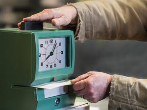 Caucasian worker punching time clock in warehouse Getty