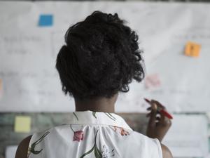 Creative businesswoman brainstorming, reviewing flow chart hanging on brick wall in office