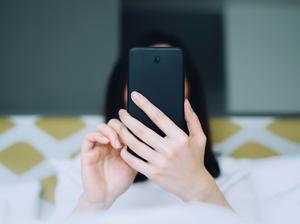 Portrait of woman using mobile phone while lying on bed