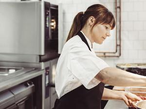 Side view of female chef preparing dish in commercial kitchen