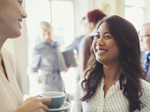 Smiling businesswomen drinking coffee and networking at business conference