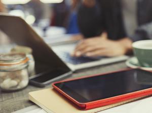 Creative businessman working at laptop behind digital tablet in cafe