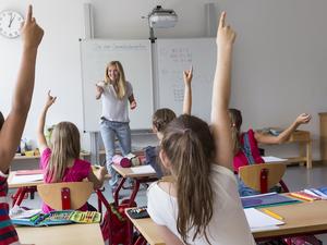 Active pupils raising their hands in class