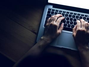 Close up of female hands working on laptop on table in the dark