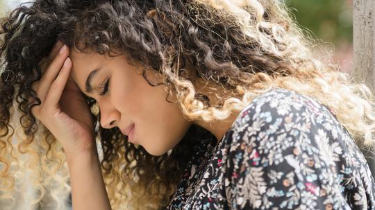 Mixed Race woman rubbing forehead