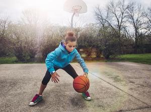 Girl on basketball court bouncing basketball