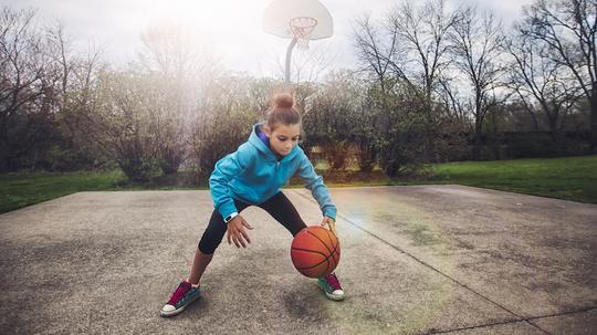 Girl on basketball court bouncing basketball