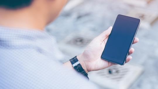 Young asian handsome businessman concentrated while reading his smartphone.