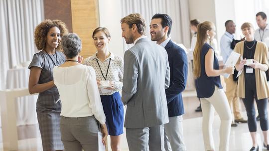 Group of business people standing in hall, smiling and talking together